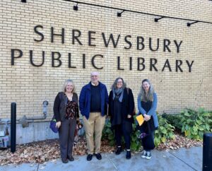 Photograph of 4 people standing in front of the Shrewsbury, MA Public Library
